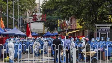 رجال إنفاذ القانون يرتدون بدلات واقية بيضاء ويستعدون لنقل السكان الذين يرتدون معدات الوقاية الزرقاء في غوانغتشو بمقاطعة غوانغدونغ جنوب الصين